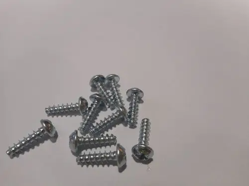 Eine Ansammlung von Metall-Schrauben auf einem weißen Hintergrund, die teilweise sichtbar oder verdeckt sind, ohne erkennbare Marke oder spezifische Maße.